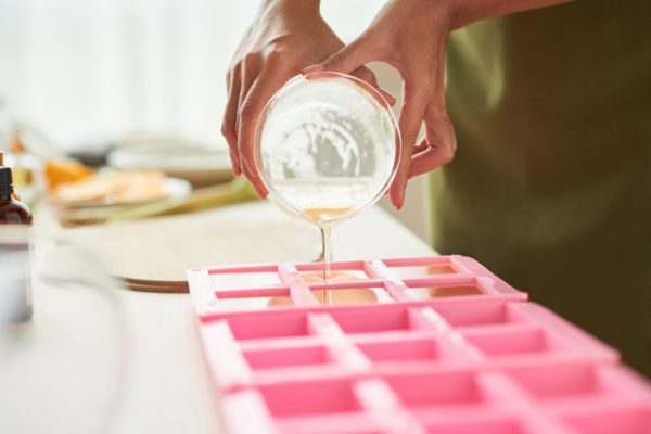 Close-up image of woman pouring soap mixture into plastic form
